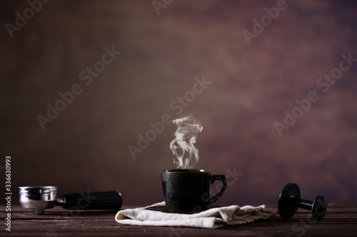 Coffee cup and utensils for coffee maker on dark brown background with copy space for text