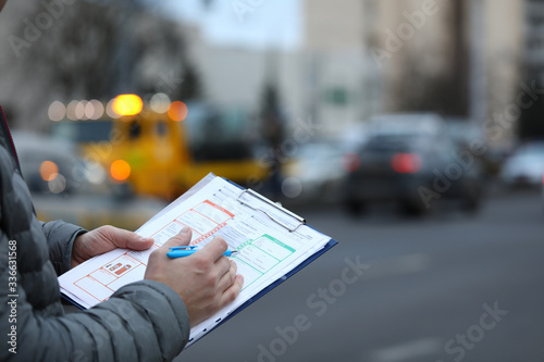 Close-up of male insurance agent filling report claim form on clipboard. Copy space in right side. Automobile crash. Process after car accident and traffic concept photo