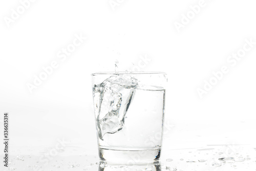 Glass with water and ice on a white background. Glass of mineral water and ice on white background.