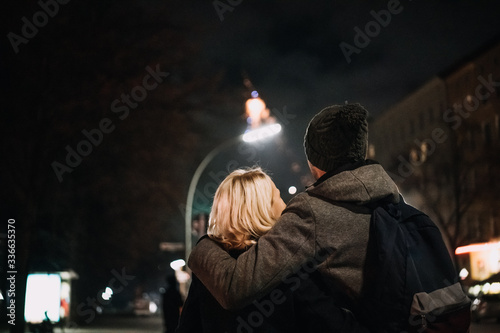 young couple enjoying new year's eve, fireworks in the background