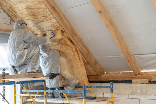 Professional worker in overalls working with rockwool insulation material