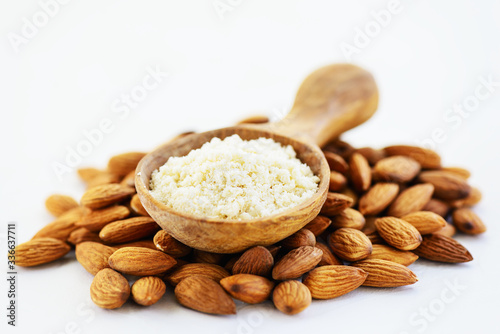 Almond flour in a wooden spoon on a pile of almonds. Gluten free food.