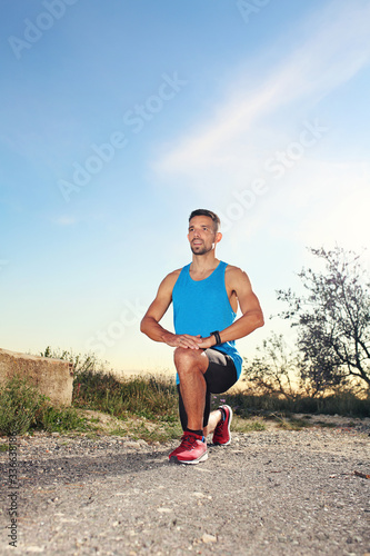 Warm up before training. A man in sports outfit performs stretching exercises.