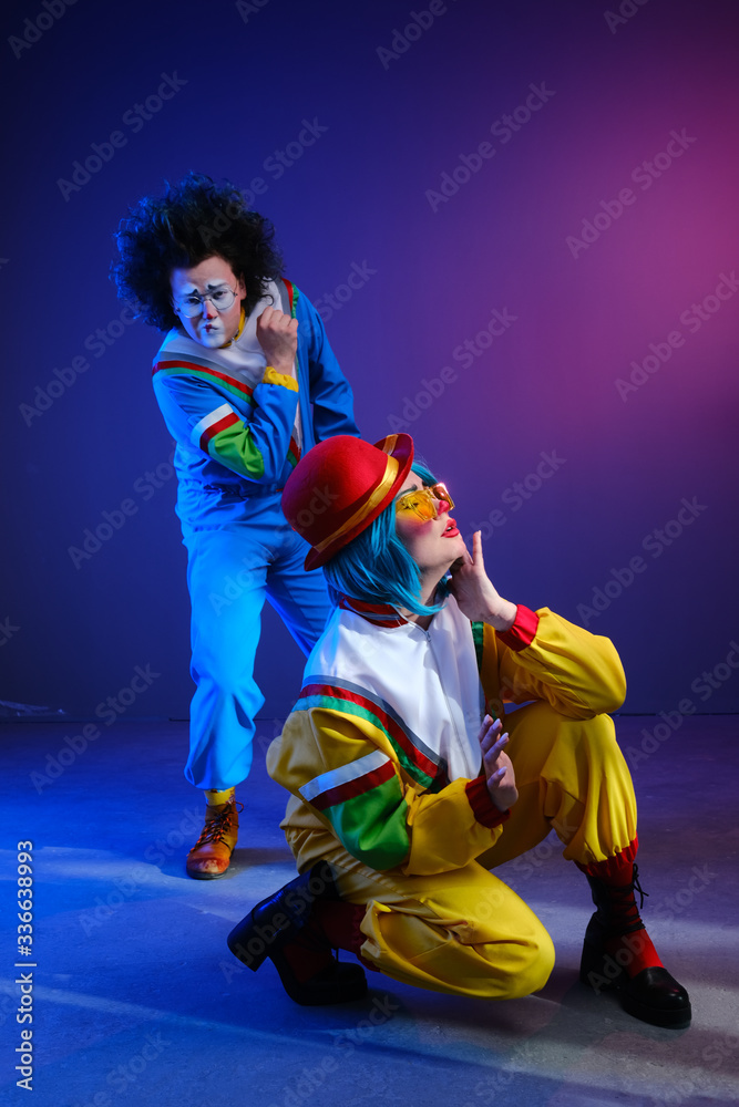 Naklejka premium Two clowns a man and a woman with makeup in bright colored tracksuits in the style of the 80s.