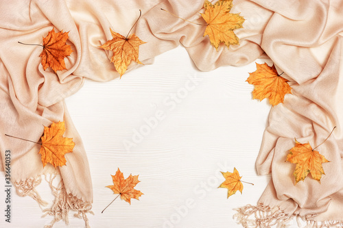 Autumn background  white wood with dry yellow autumnal season leaves of maple tree  cozy textile scarf. Copy space. Top view.