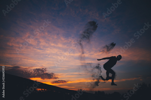 Silhouette of a man jumping in sand at sunset