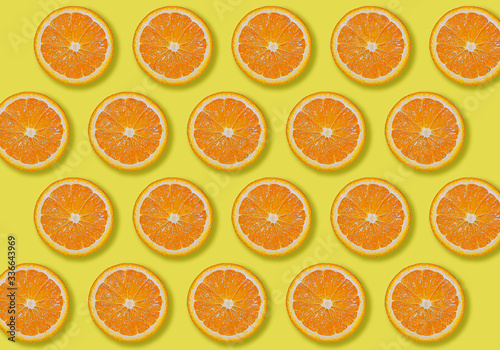 Image of patterned fresh orange sliced on yellow background