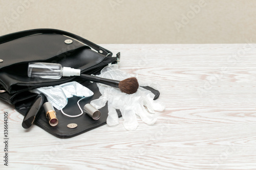 Close up of woman's purse with antibacterial hand sanitizer, medical mask, gloves to prevent spread of bacteria. Personal hygiene concept to 
avoid infections corona virus with copy space. photo