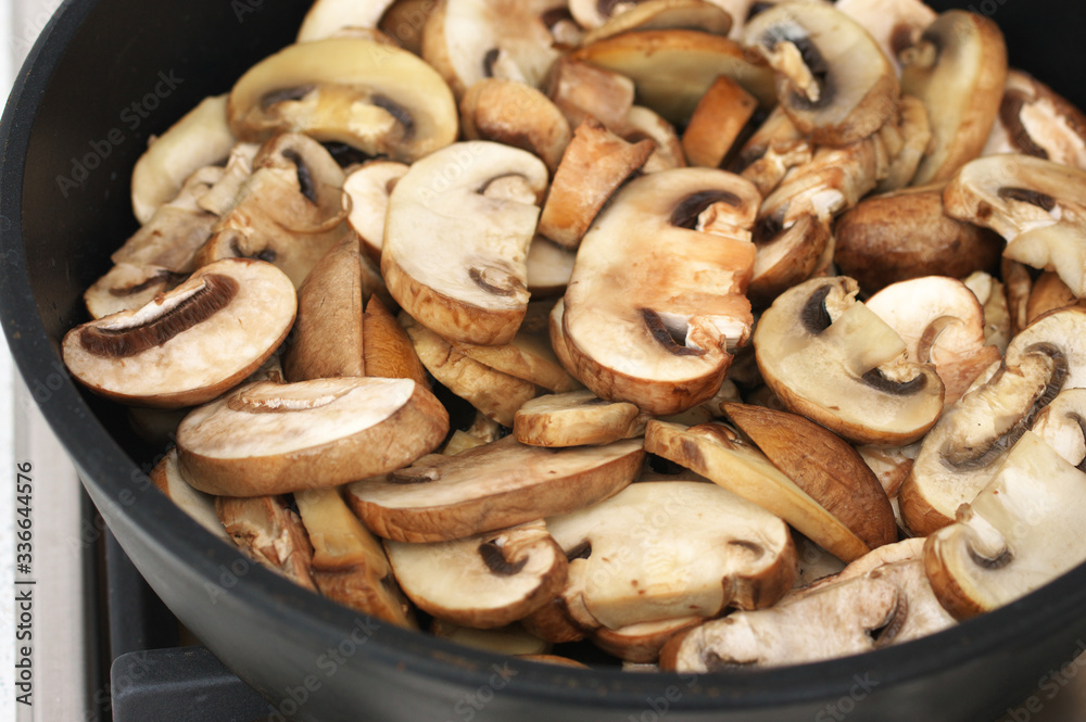 Chopped champignon mushrooms frying in pan Chopped champignon mushrooms frying in pan
