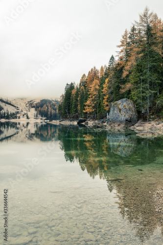 Famous Lago di Braies lake in Italy on a foggy weather with beautiful reflections in autumn season