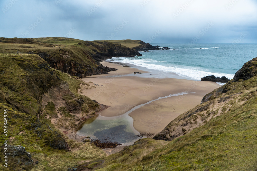 Sandy beach with a river and cliffs around