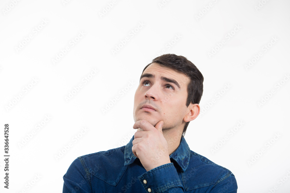 Portrait of unsure, perplexed man looking up and thinking for a solution. Thoughtful expression of a young man over white background.