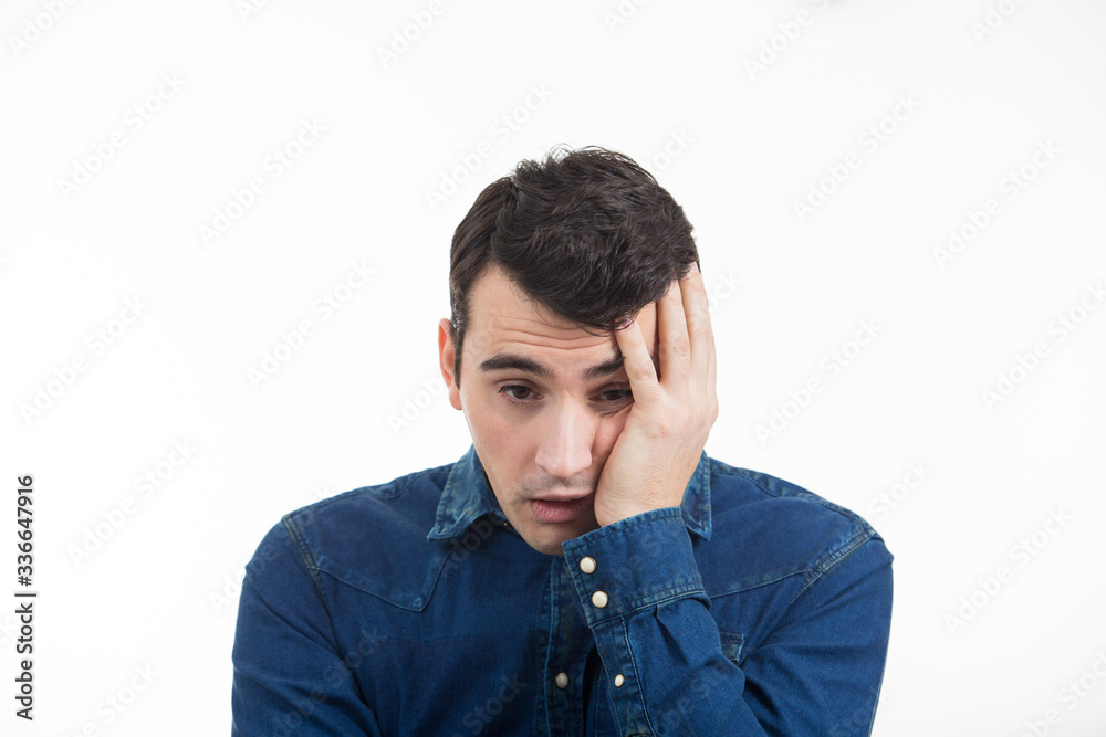 Stressed young man portrait, sad, bothered, holding hands on his head  isolated on white background.