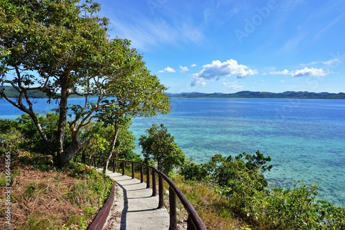 Pass Island - paradise in Philippines; walking path among the trees and grass with amazing sea view