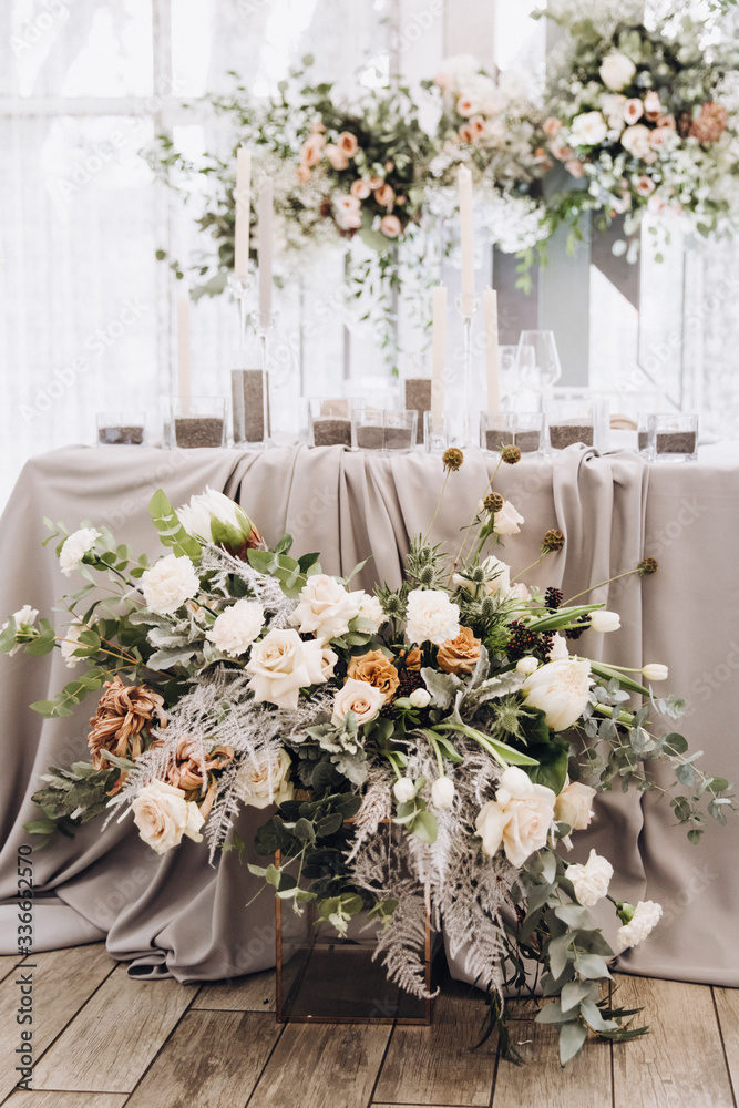 Stylish wedding floristics. Banquet tables decorated with arrangements of flowers, herbs and candles