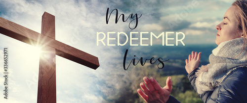 Christian worship and praise. Cross with sunset sky background. Easter. Woman praying. M y redeemer lives.