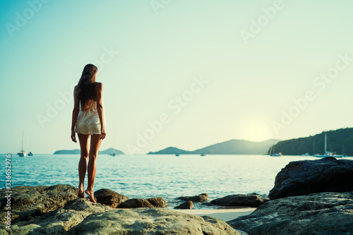 Young woman with long hear standing on sea beach enjoying the view.