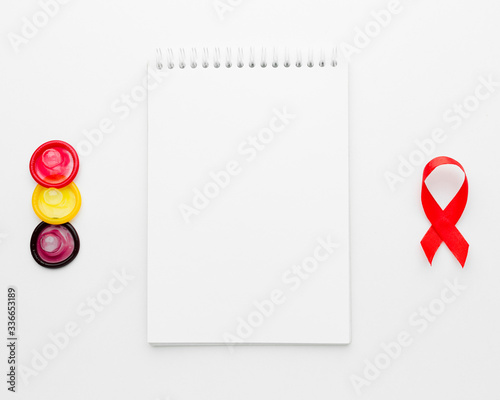 Arrangement of colorful condoms with empty notepad