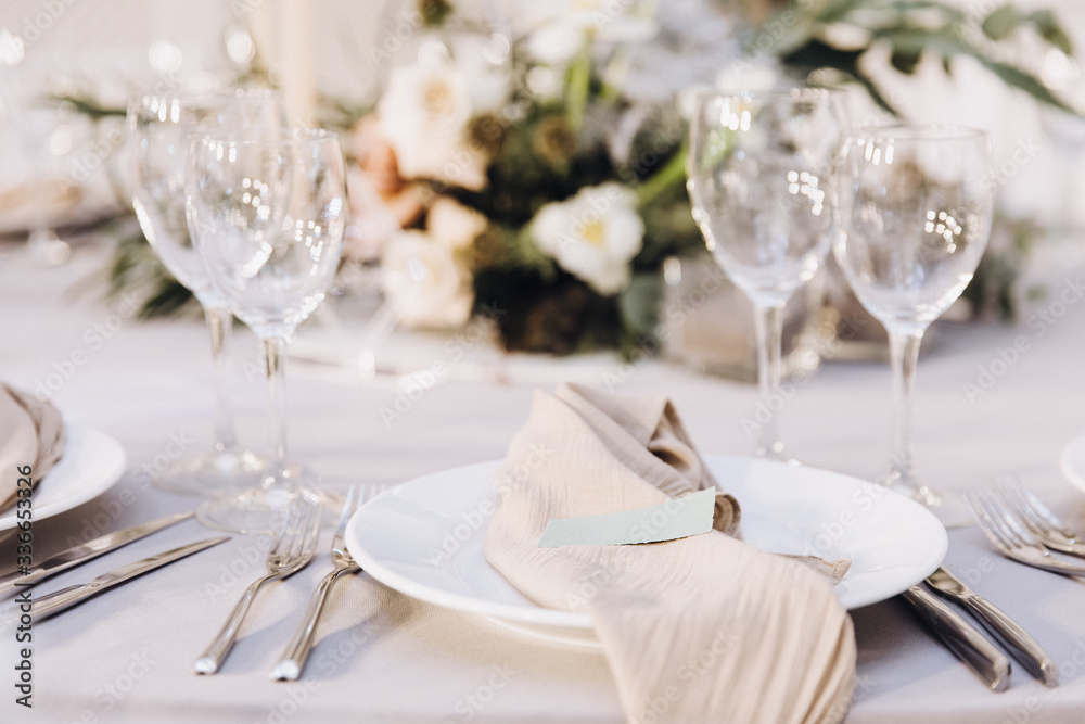 Table setting. On the banquet table there are plates with napkins and name cards, glasses and cutlery Table setting. On the banquet table there are plates with napkins and name cards, glasses and cutlery