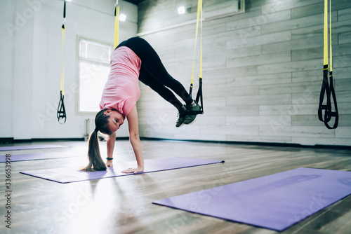 Young woman looking away and doing handstand with rubber expander