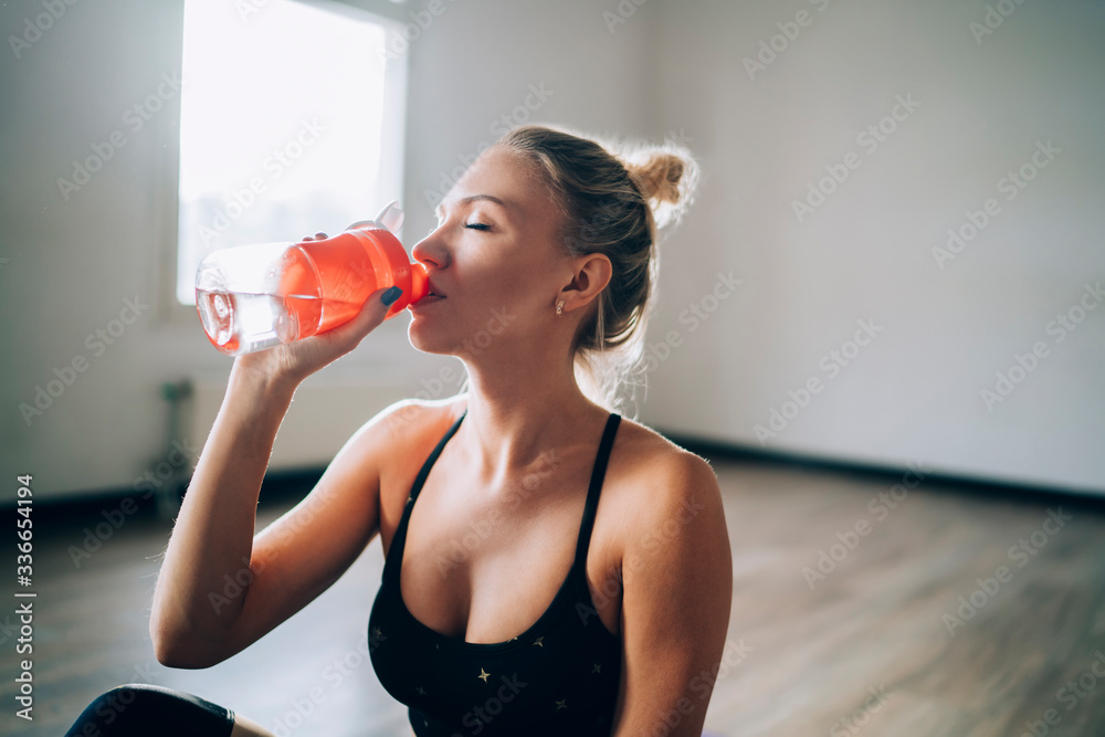 Exhausted sportive female resting and drinking water Exhausted sportive female resting and drinking water