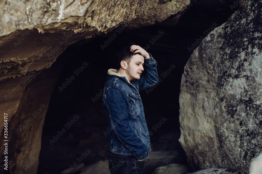 Sad man stands in a dark cave. The concept of loneliness Sad man stands in a dark cave. The concept of loneliness