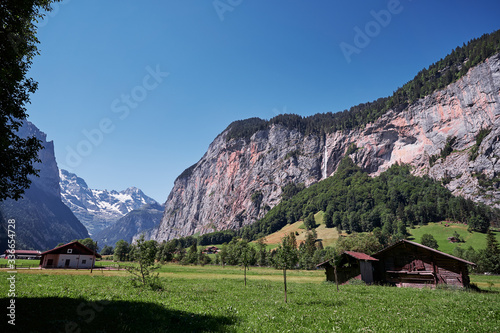 Beautiful summer landscape with barn on green field, Swiss Alps Mountains.