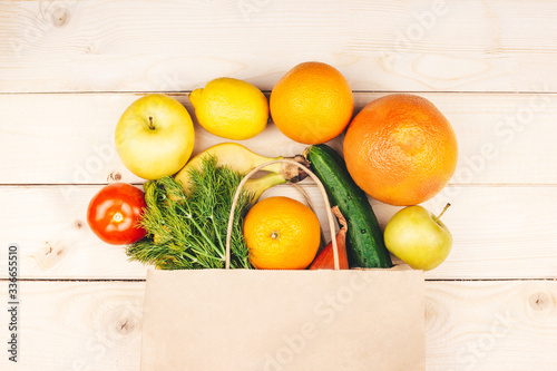 Paper shopping bag with organic vegetables and fruits flat lay on wooden background top view. Healthy food. Grocery store delivery, online supermarket concept. Web banner template. Stock photo.