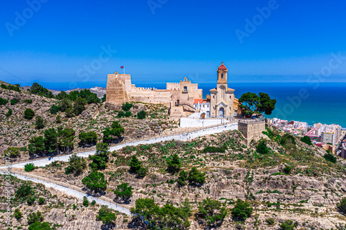 Aerial drone photo of a beautiful church/castle aka Castello on top of a mountain in Andalusia Spain in a city called Cullera, with a beautiful background of blue sea 