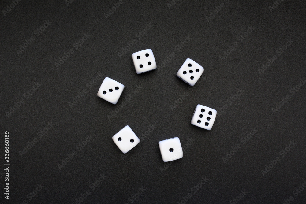 Six white dice placed on a dark metallic surface, copyspace for text. Six white dice placed on a dark metallic surface, copyspace for text.