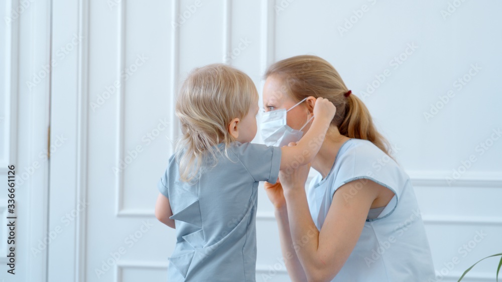 Concept, family during quarantine self-isolation. Mom puts her son in a mask for protection. Concept, family during quarantine self-isolation. Mom puts her son in a mask for protection.