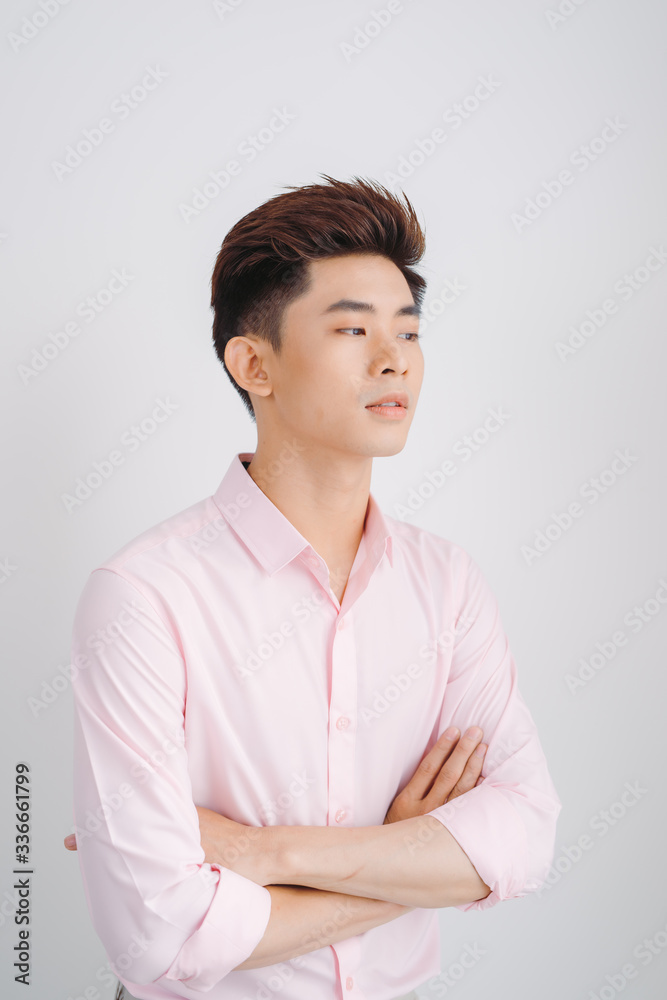Smiling Asian man wearig pink shirt standing with hands folded over white background Smiling Asian man wearig pink shirt standing with hands folded over white background