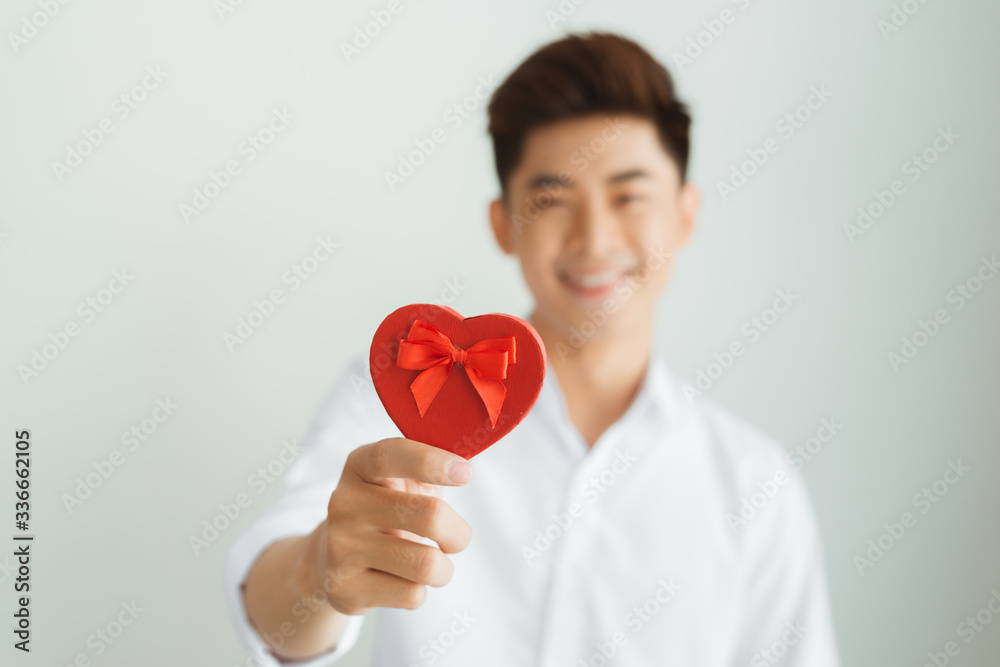 Handsome young man holding red heart box on white background Handsome young man holding red heart box on white background