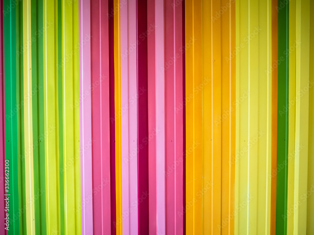 Fototapeta premium Bright multicolored metal wall painted in vertical stripes of different colors. Artistic and perfect for backgrounds, wallpapers, backdrops. Urban street art from modern artists.