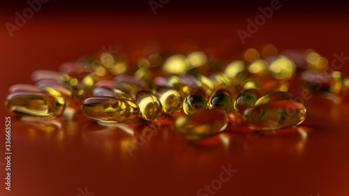 fish oil capsules on a red background close-up with a small roughness of sharpness. blurred background on the theme of health
