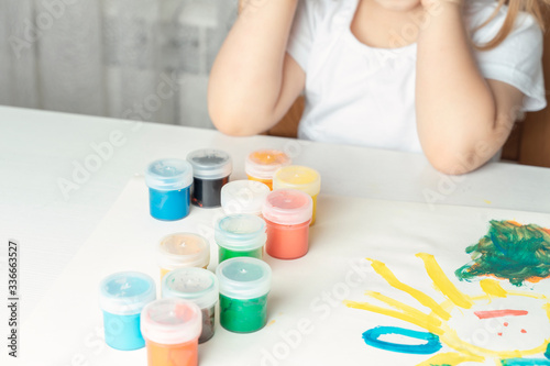 what to do for a child during the period of quarantine and self-isolation, jars with colored gouache, children’s drawing, a child in the background in the background