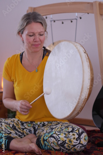 Close up of a woman in a yellow T-Shirt playing the gong drum in a yoga class.