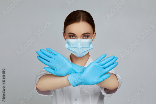 Canvas-taulu woman doctor in mask and rubber gloves doing stop gesture on gray background