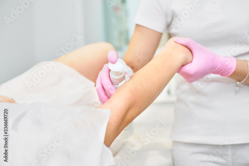 Depilation and beauty concept - beautician waxing young woman with liquid sugar at spa. depilation with colored shugaring paste © izikmd