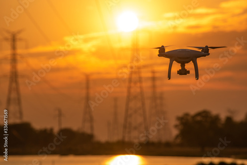 Drone surveying High voltage towers the sunset background