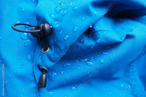 Closeup of water drops on bright blue fabric and elastic band with waterproof design to protect fabric of the cloth from humidity and to offer easy cleaning to users Fabric texture with design concept