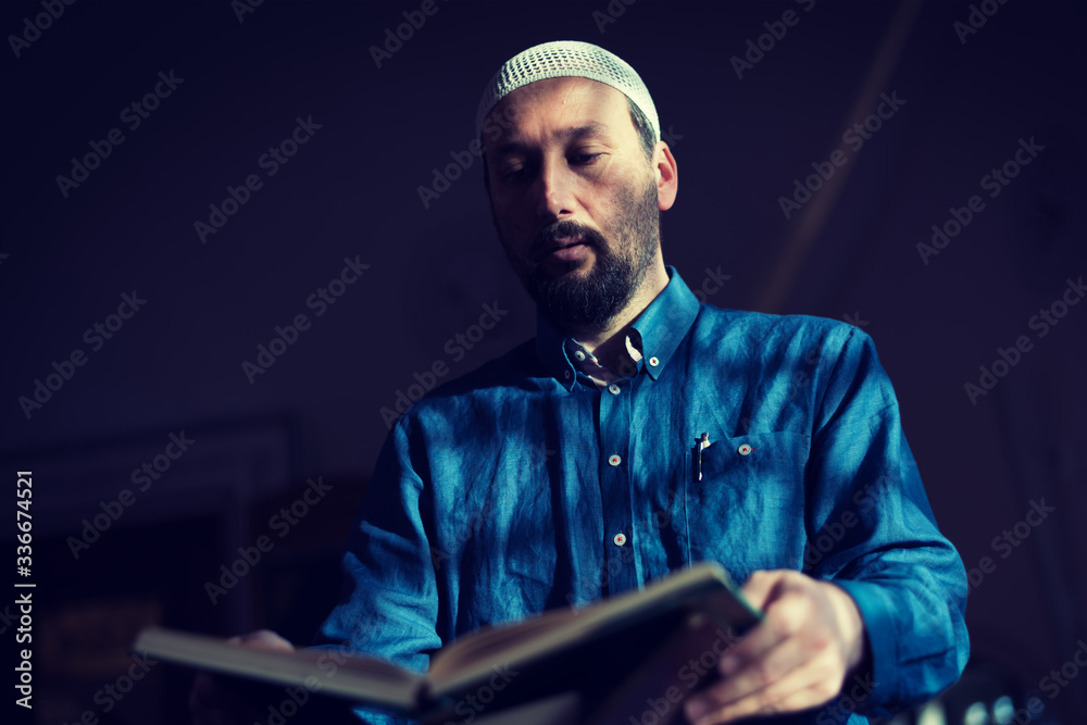 Young Arabic Muslim man reading Koran and praying. Religious muslim man reading holy koran inside the mosque. Young Arabic Muslim man reading Koran and praying. Religious muslim man reading holy koran inside the mosque.