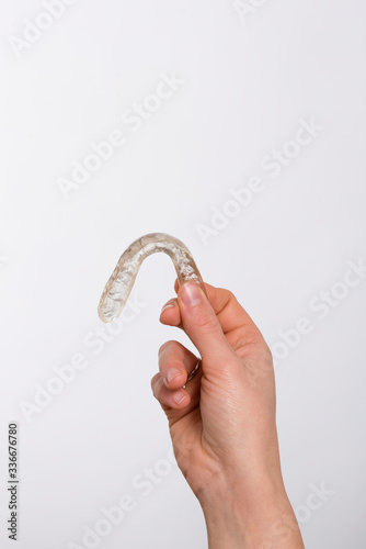 Mano femenina sosteniendo una férula dental de descarga para tratar el bruxismo. Fondo blanco