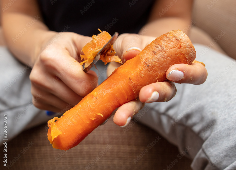Girl peeling boiled carrots with a knife. Girl peeling boiled carrots with a knife.