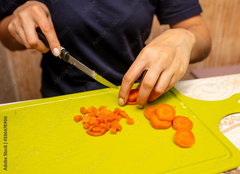 Girl cuts boiled carrots with a knife Girl cuts boiled carrots with a knife