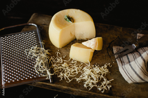 delicious cheese wheel grated on dark background.