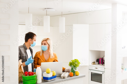 Order food online. Young beautiful couple in kitchen ordering food online from restaurant. Family of two using laptop. Young woman paying with credit card. Nice loft kitchen interior with light bulbs