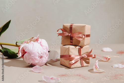Pink peony flower and two gifts on pastel background. Perfect selfcare gift for a girlfriend or wife.