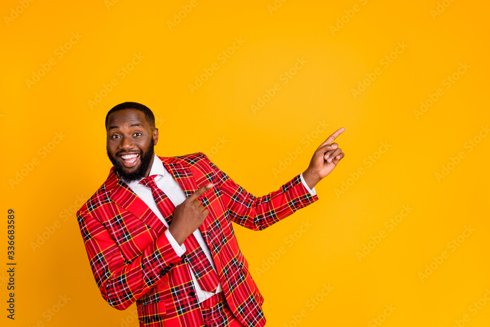 Photo of funny sales person dark skin guy indicating fingers side empty space advising novelty product wear plaid costume blazer shirt tie pants isolated yellow color background Photo of funny sales person dark skin guy indicating fingers side empty space advising novelty product wear plaid costume blazer shirt tie pants isolated yellow color background