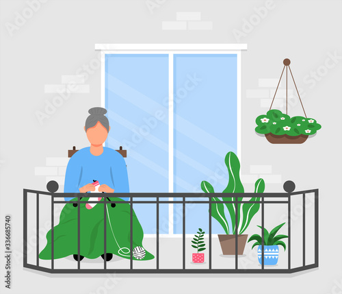 An elderly woman is resting for knitting while sitting on the balcony. An old woman sits on a balcony among plants. Pastime in the fresh air.